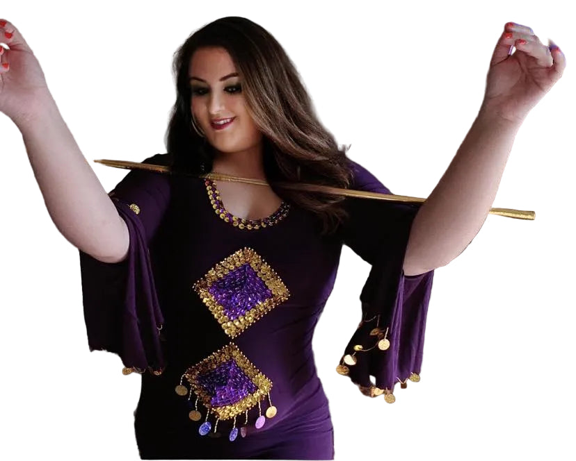 Woman wearing a purple outfit with gold embellishments, holding a wooden stick.