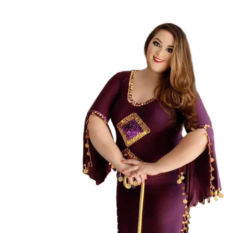 Woman in a purple dress with gold accents posing indoors.