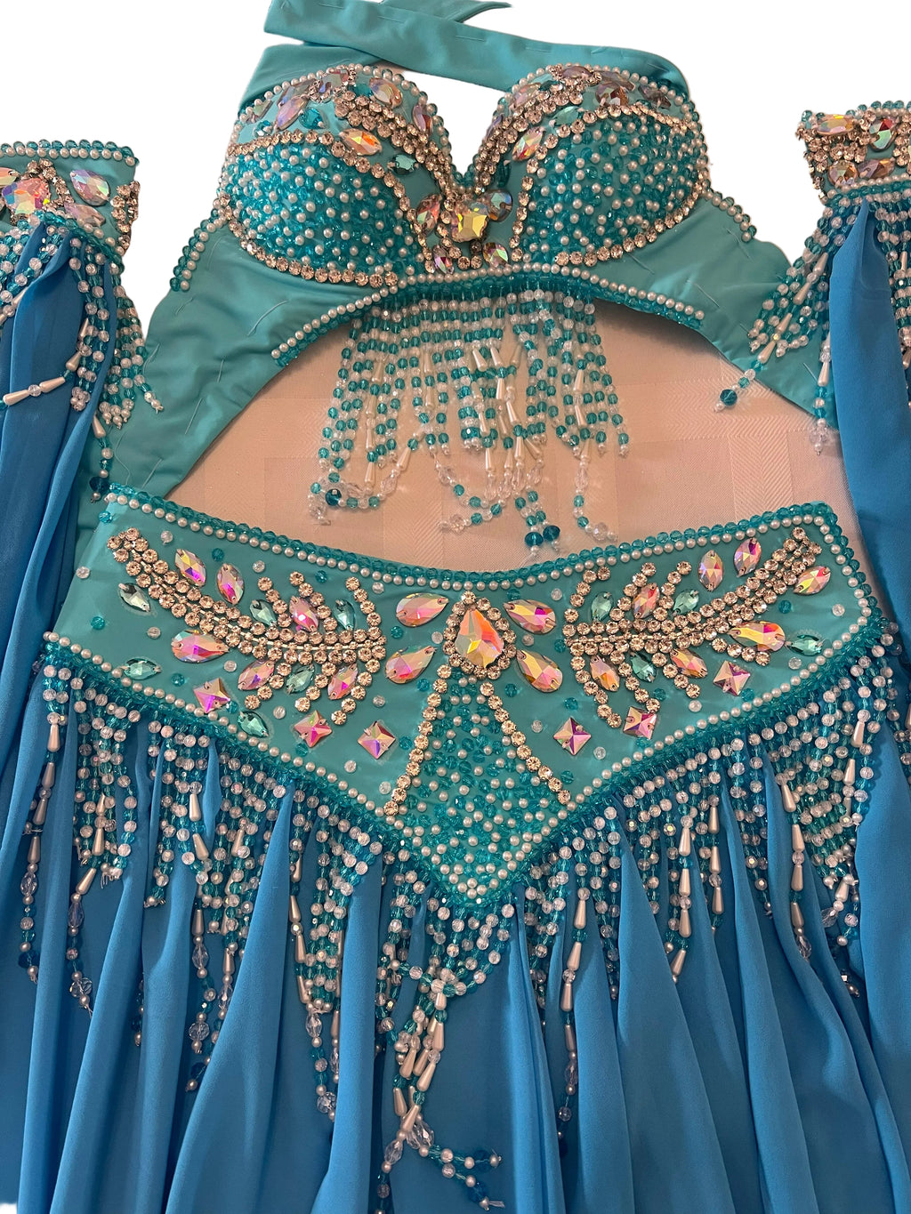 A turquoise and blue belly dance costume set with intricate beadwork, sequins, and rhinestone embellishments, laid flat on a light-colored surface.