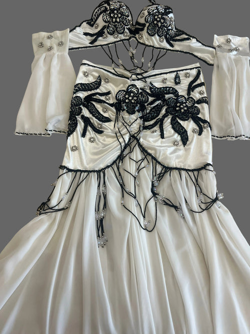 White Egyptian belly dance costume with black floral embellishments, beaded drapes, chiffon skirt and matching sleeves