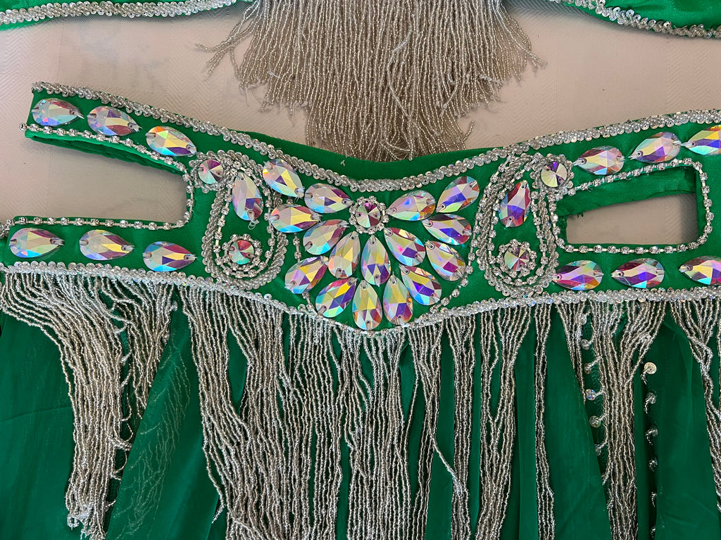 Decorative green fabric with silver beads and fringes on a beige background