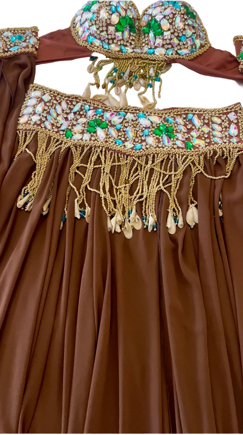 A close-up of a brown satin belly dancing costume with intricate gold, white, and green beaded embellishments and dangling tassels.