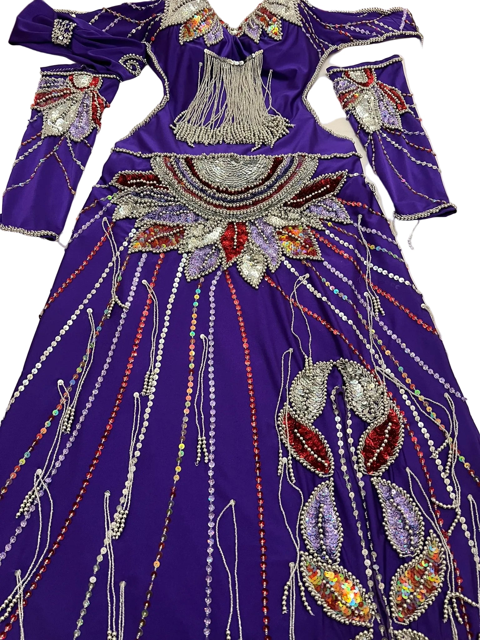 Decorative purple dress with intricate beadwork on a white surface