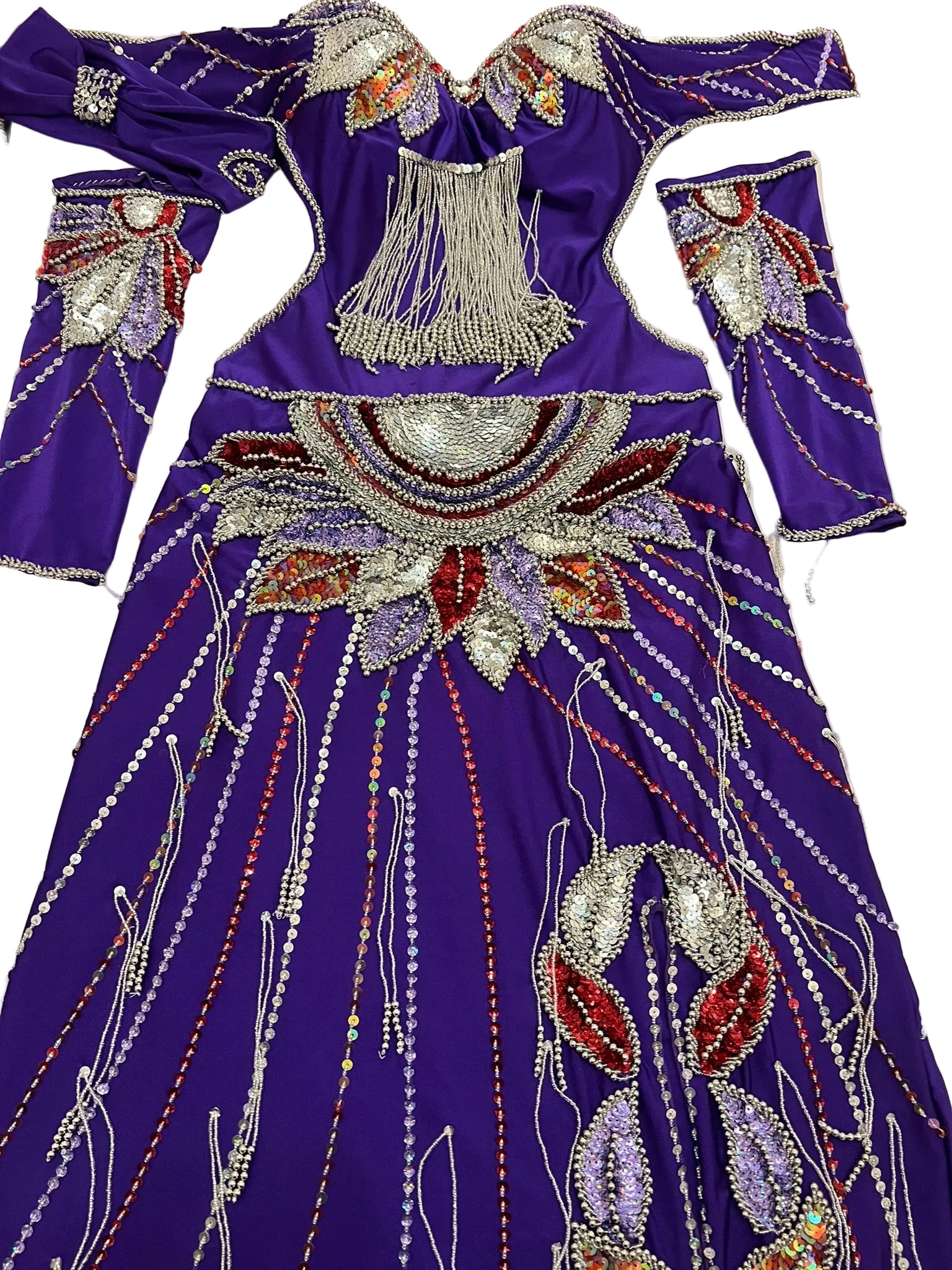 A purple belly dance costume with intricate beadwork and sequins displayed on a table.