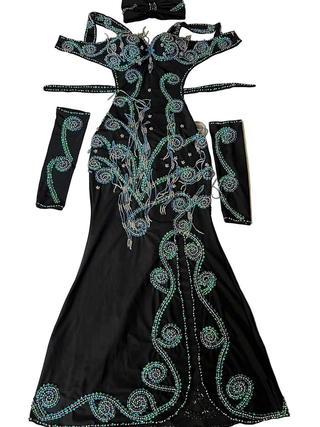 A custom-made belly dance costume laid out on a flat surface, consisting of a black one-piece dress with green embellishments, arm pieces, and a headpiece.