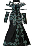 A custom-made belly dance costume laid out on a flat surface, consisting of a black one-piece dress with green embellishments, arm pieces, and a headpiece.