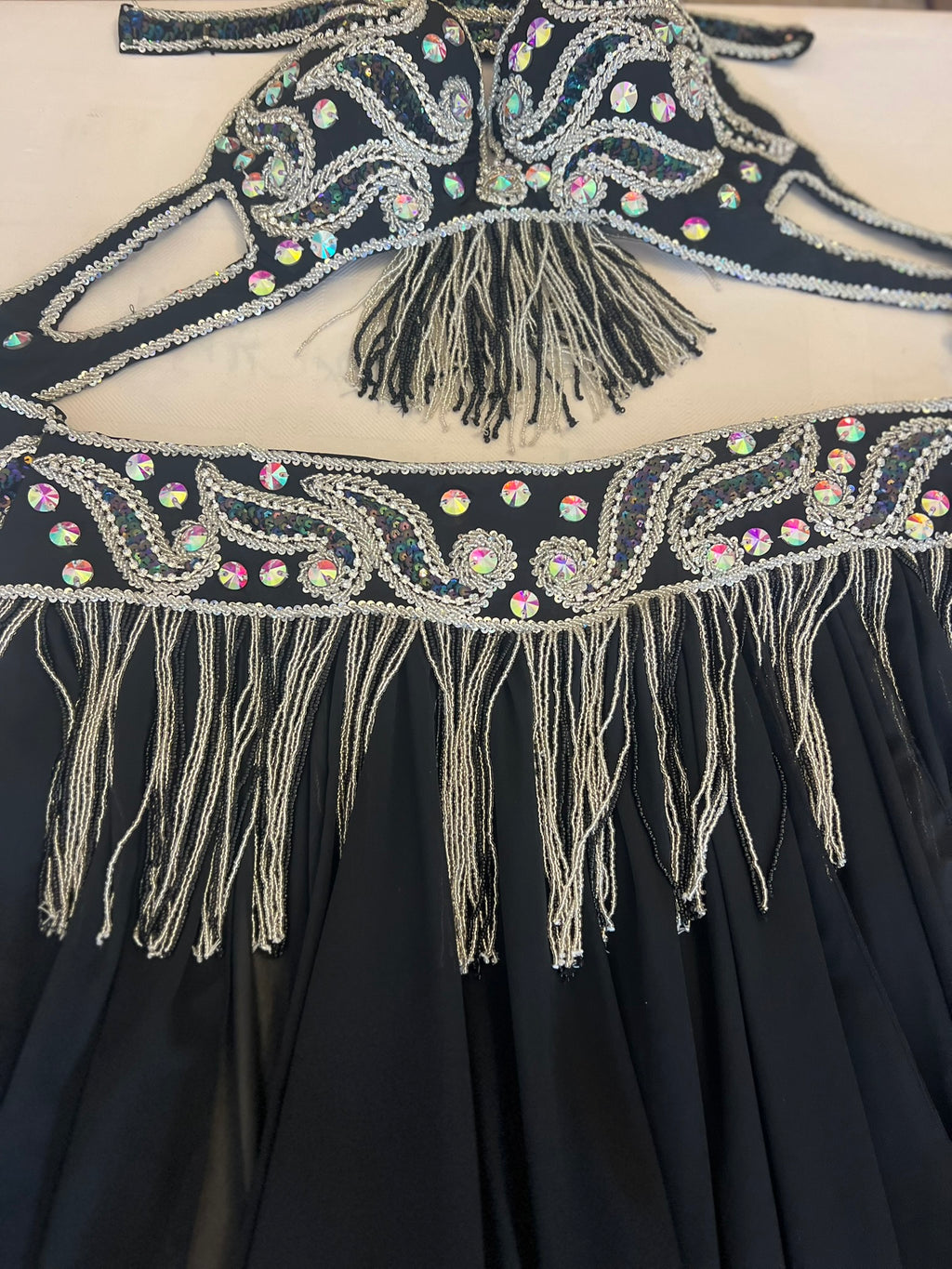 Black dress with intricate beadwork and fringes on a white background