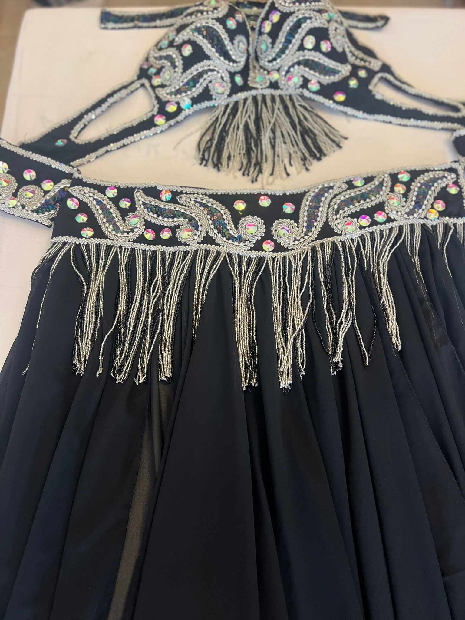 Black dress with intricate beading and fringing on a white background