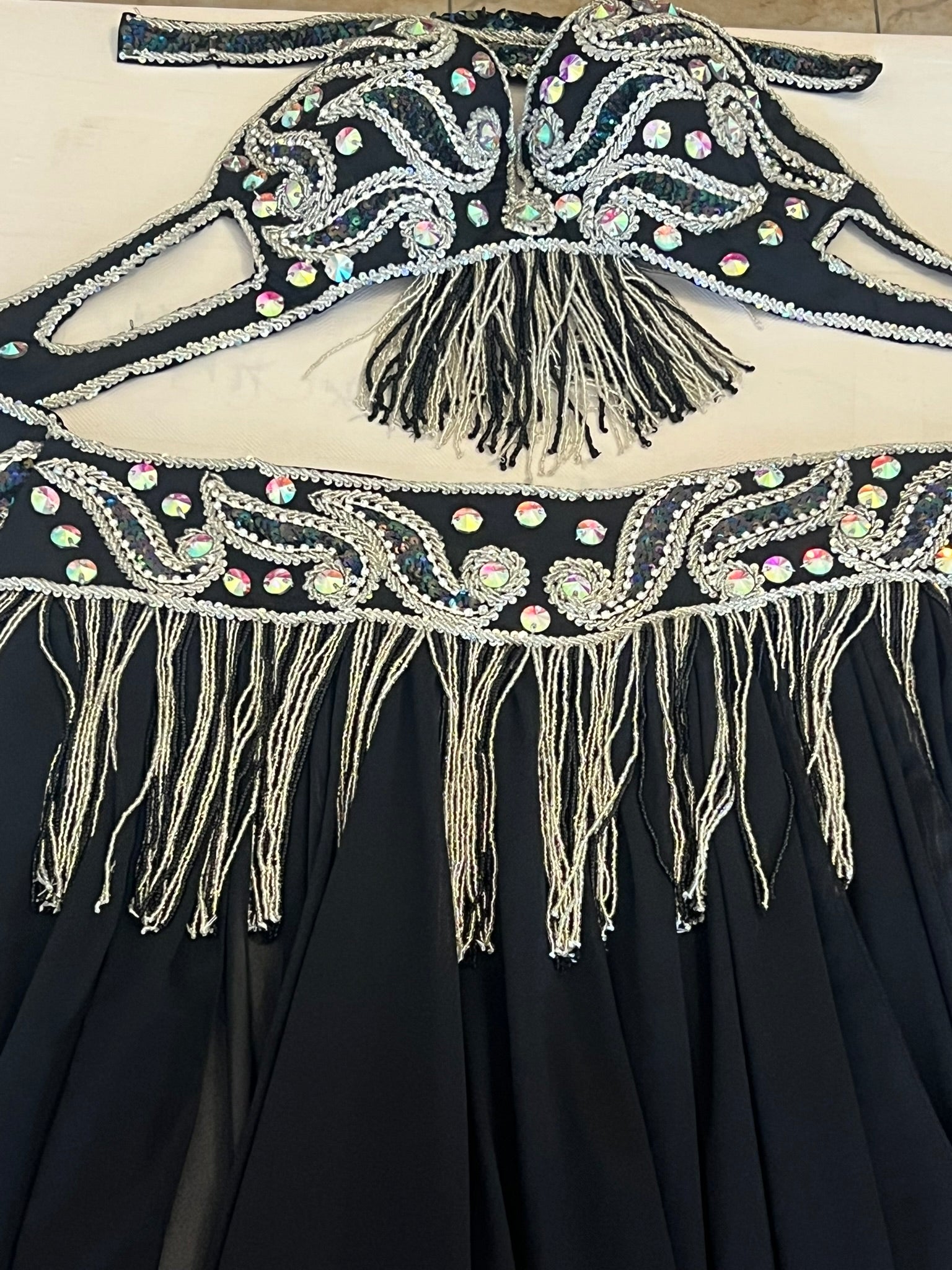 Black dress with intricate beadwork and fringes on a white background
