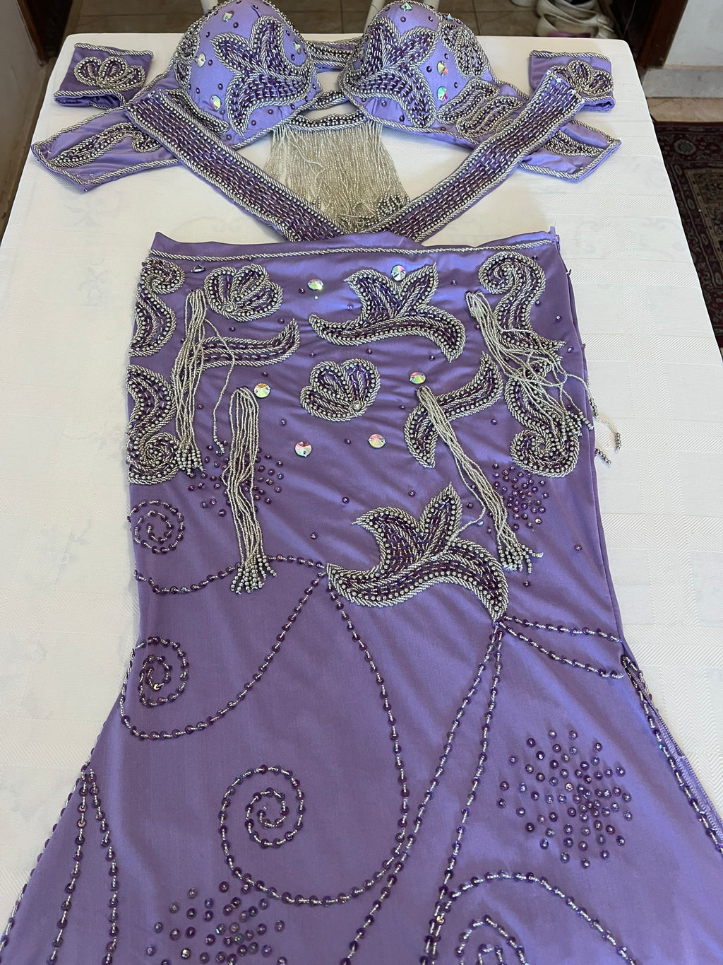Decorative purple dance outfit with intricate beadwork on a white surface