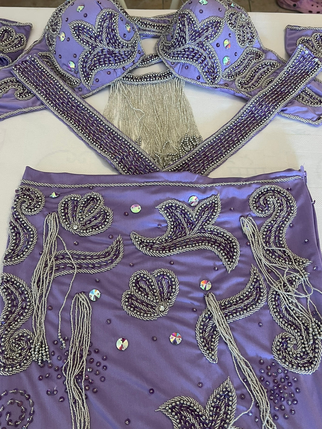 Decorative purple dancing skirt with intricate silver embroidery and tassels on a white background