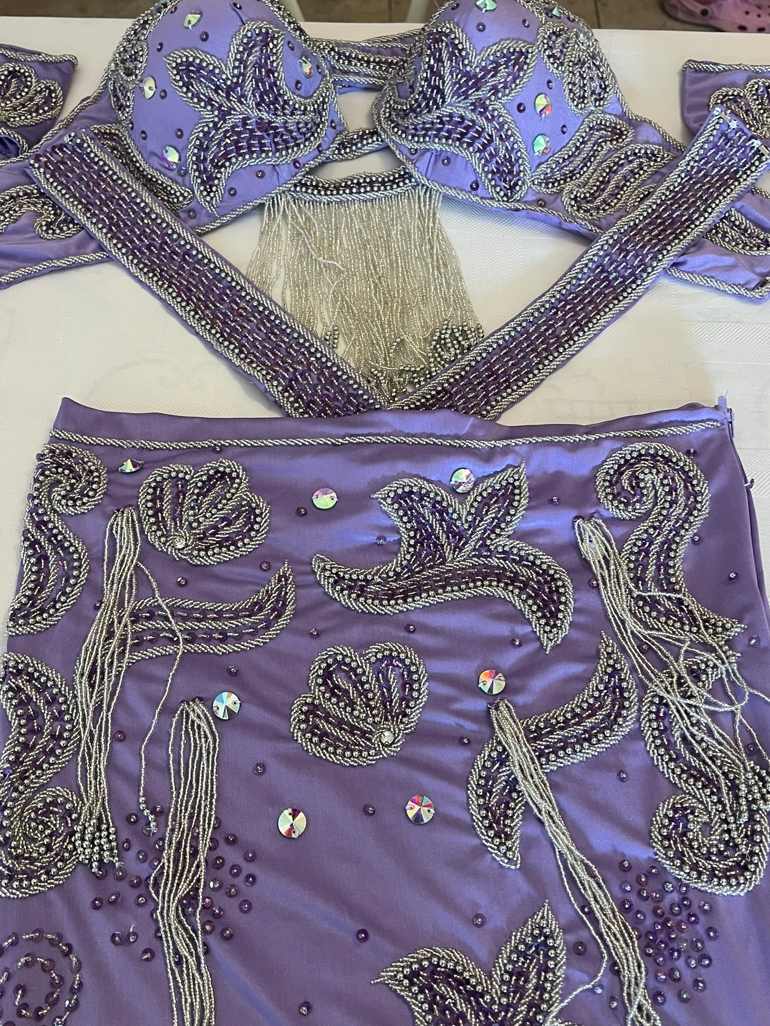 Decorative purple dancing skirt with intricate silver embroidery and tassels on a white background