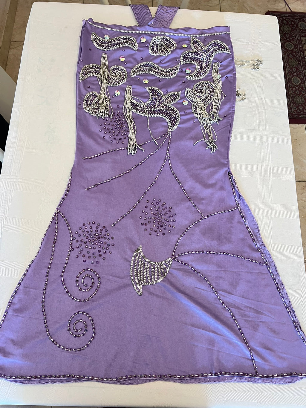 Purple oriental dance dress with intricate silver embroidery on a white surface
