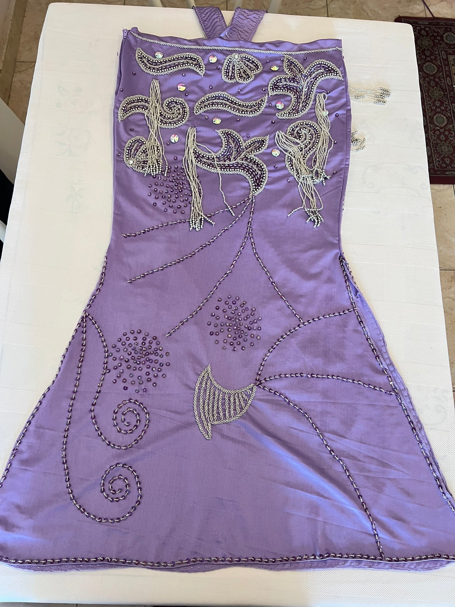 Purple oriental dance dress with intricate silver embroidery on a white surface
