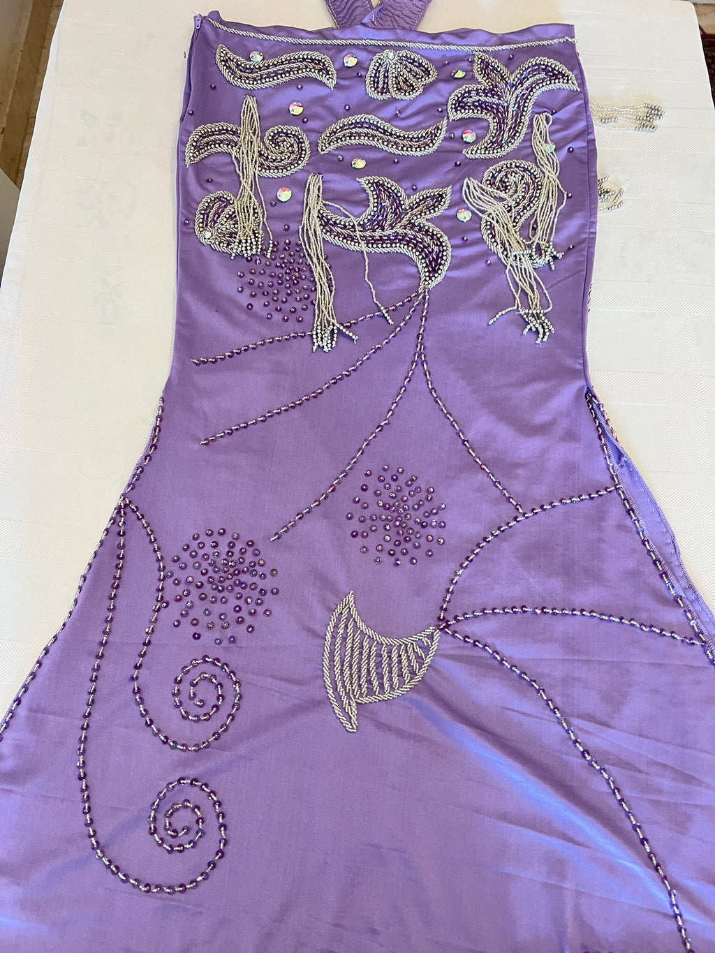 Purple dress with intricate beadwork on a white surface