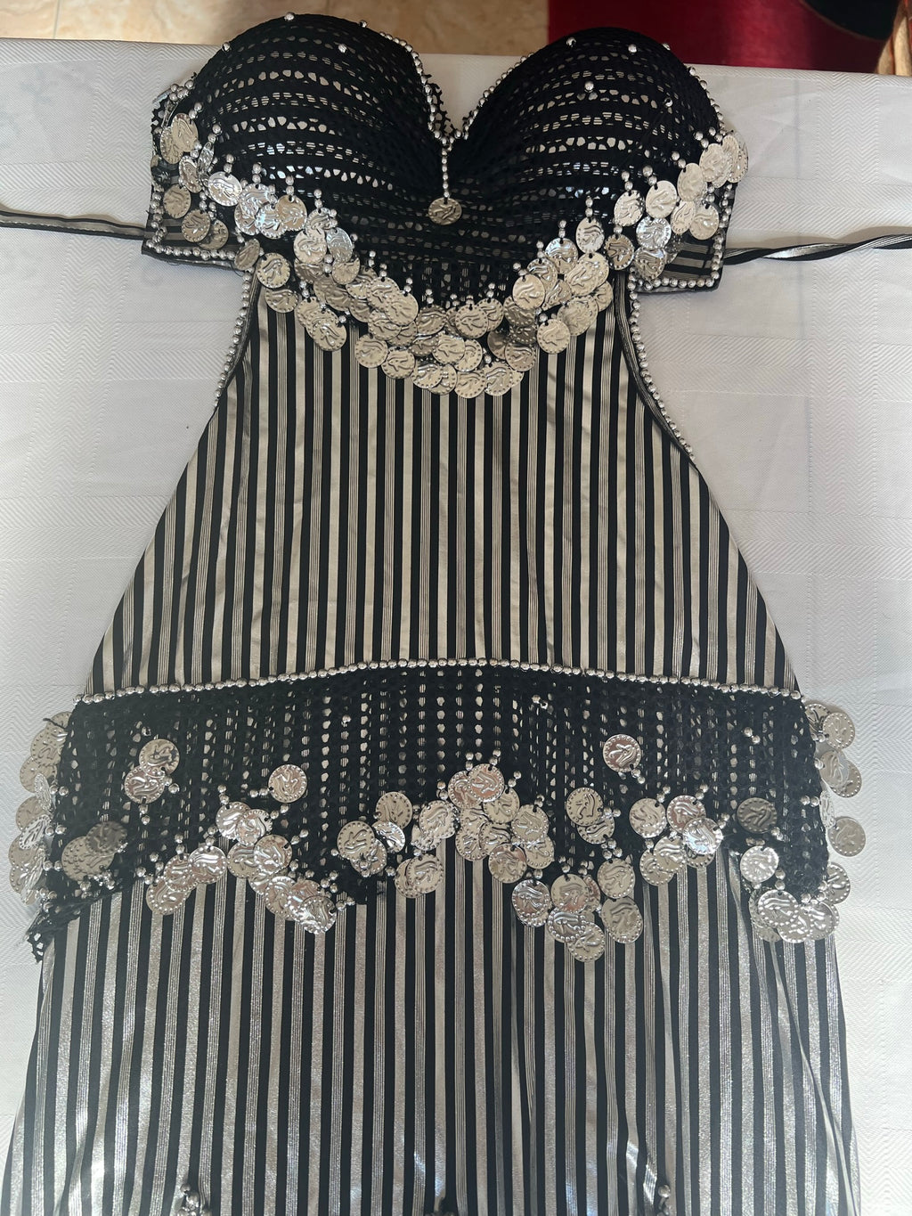 A traditional Egyptian belly dance costume featuring black and white stripes with elaborate handmade embroidery and sequins.