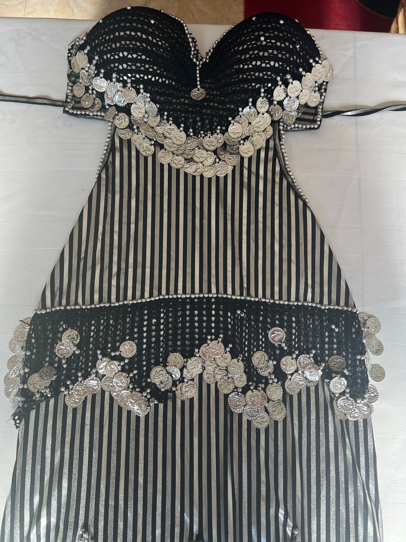 A traditional Egyptian belly dance costume featuring black and white stripes with elaborate handmade embroidery and sequins.