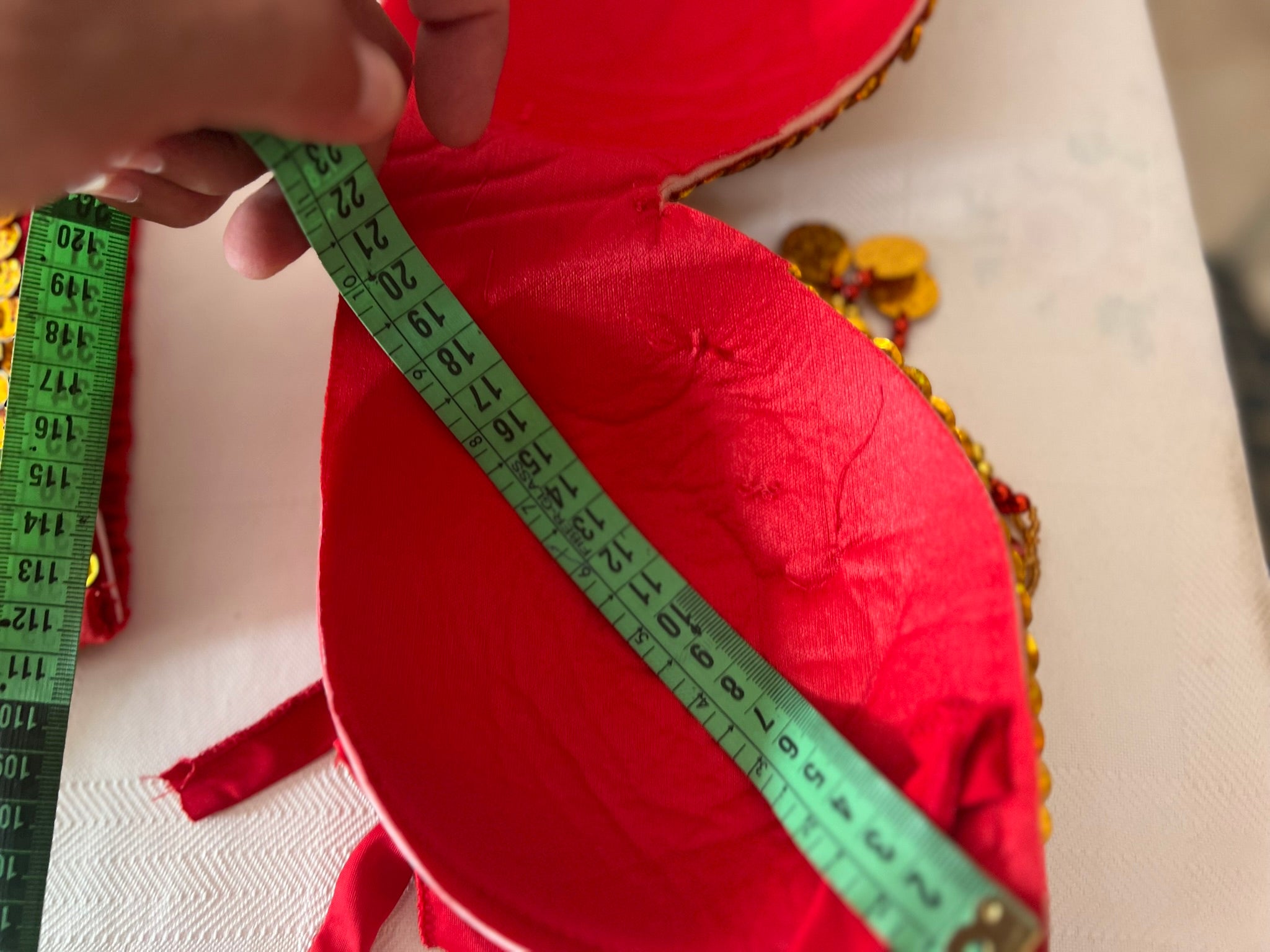 Red fabric with a green measuring tape being used to measure it