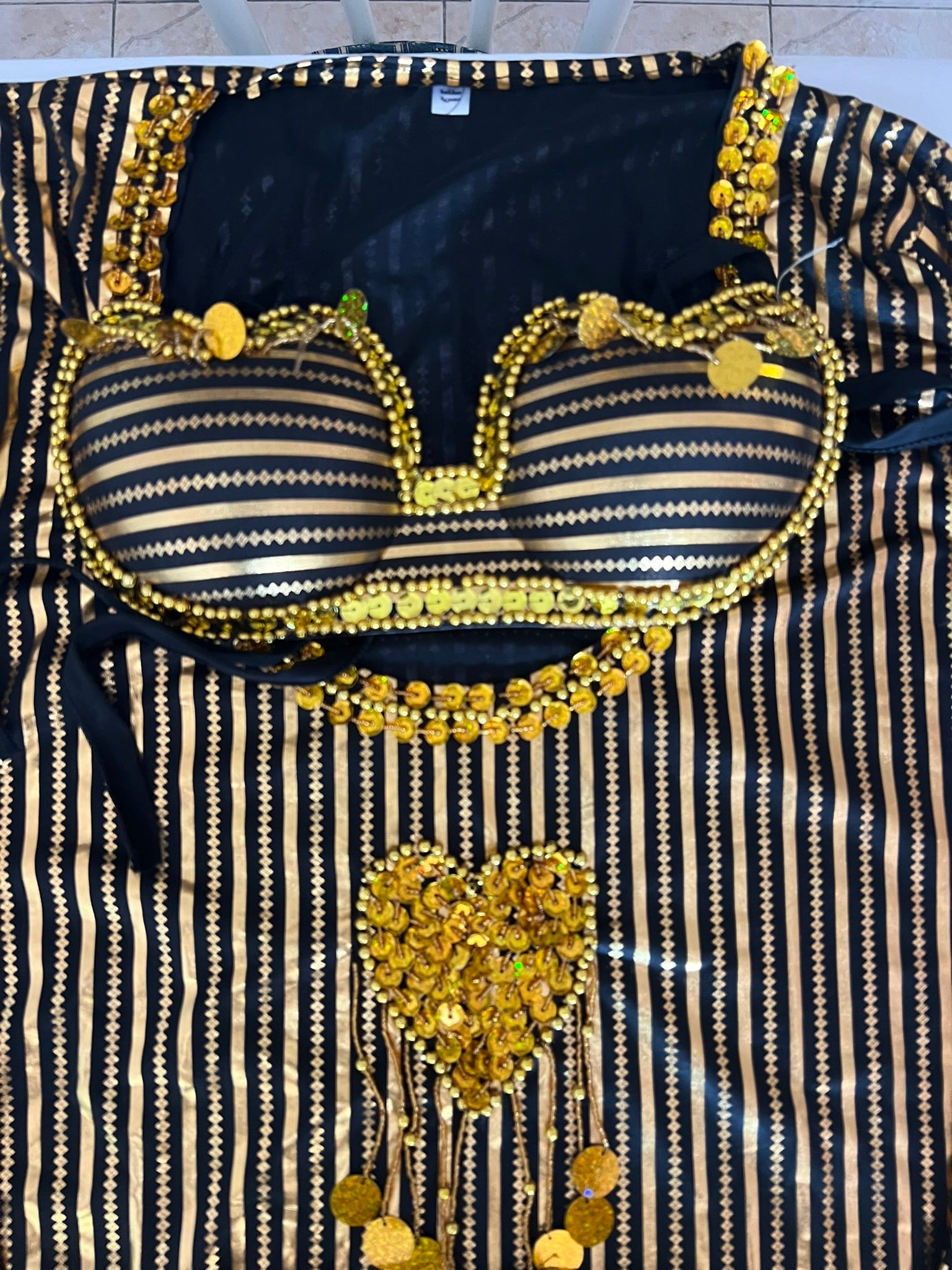 Black and gold striped garment with decorative elements on a flat surface