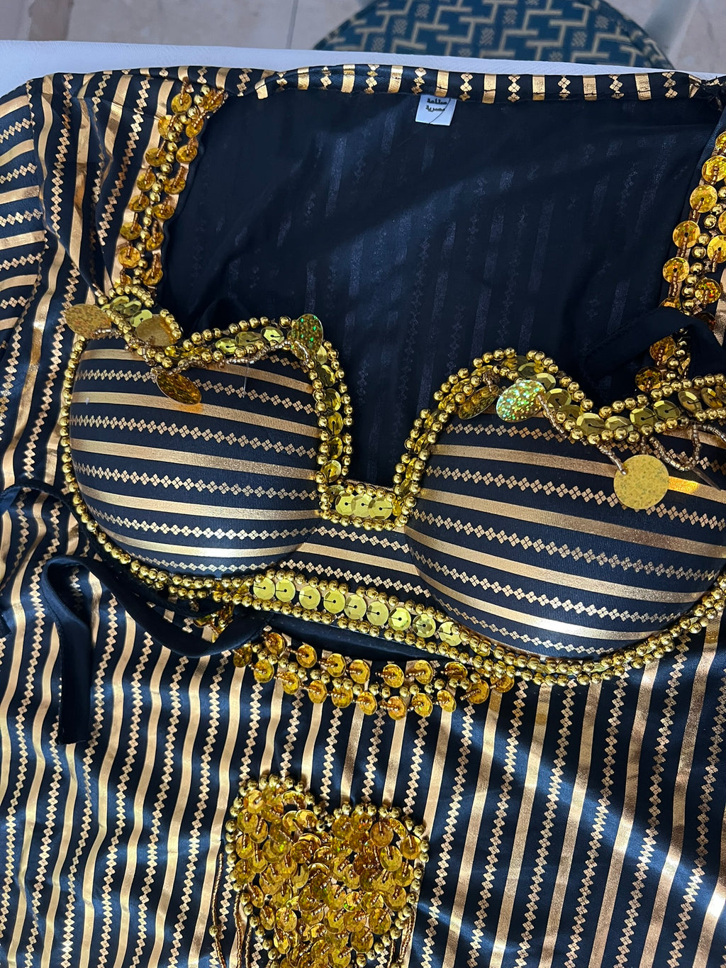 Black and gold patterned fabric with decorative elements on a plain background