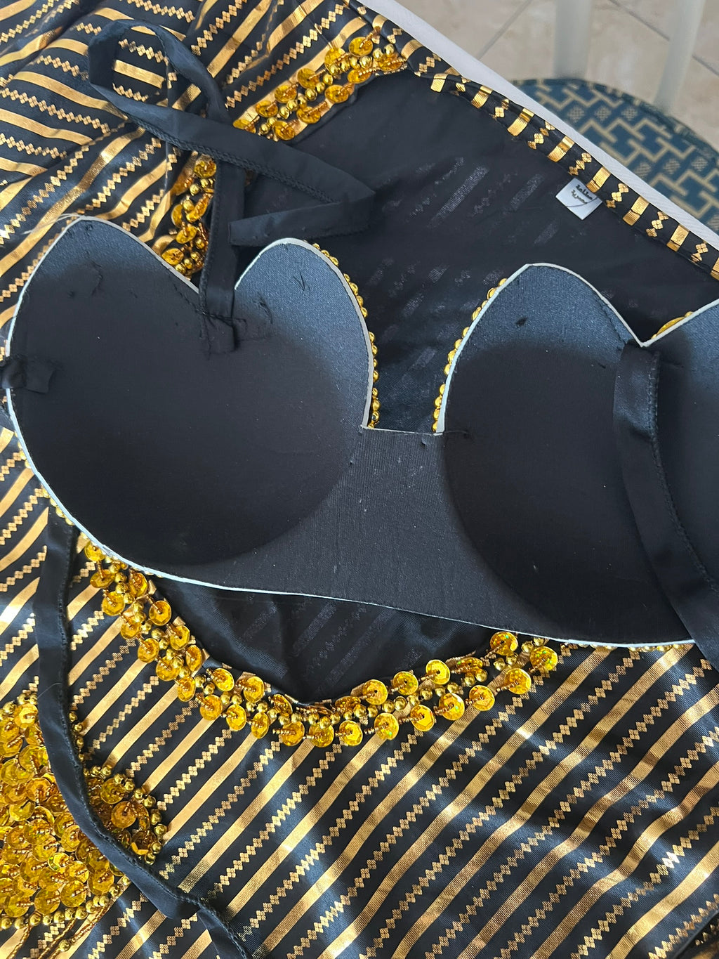 Black bra with gold embellishments on a patterned surface