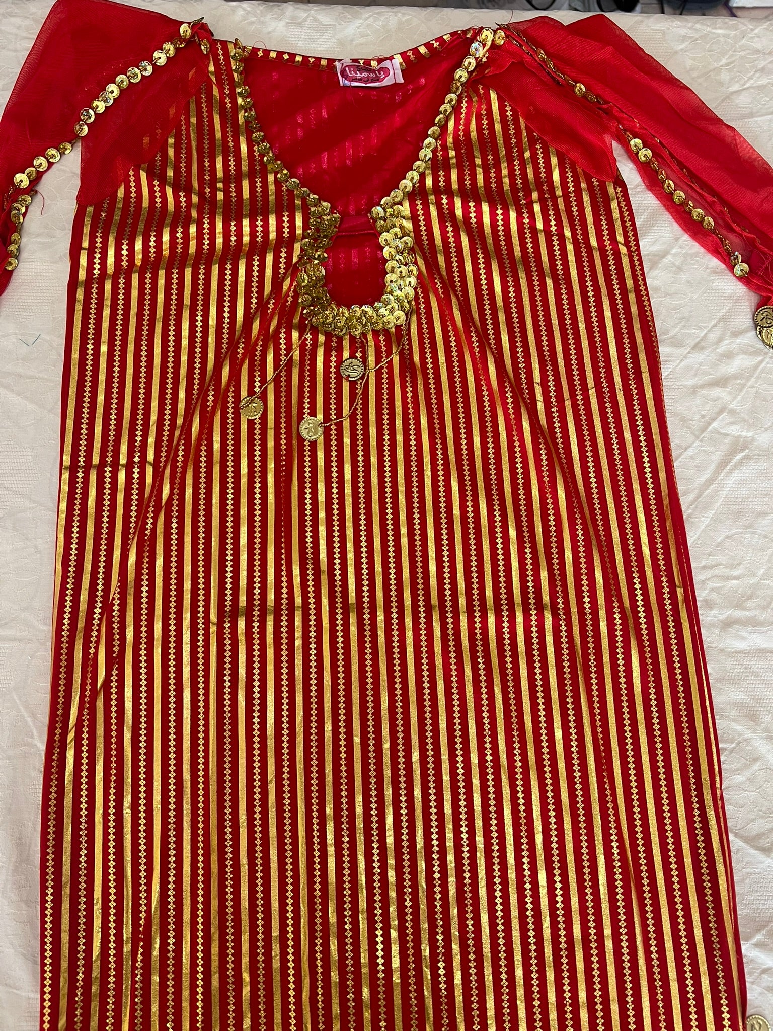 Red and gold traditional outfit with decorative elements on a white background