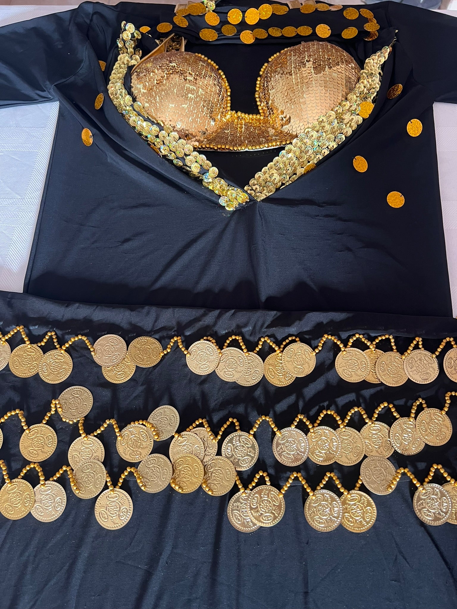 Black fabric with gold embroidery and coin patterns on a white background