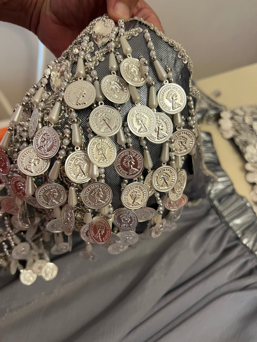 Hand holding a decorative item with coins and beads