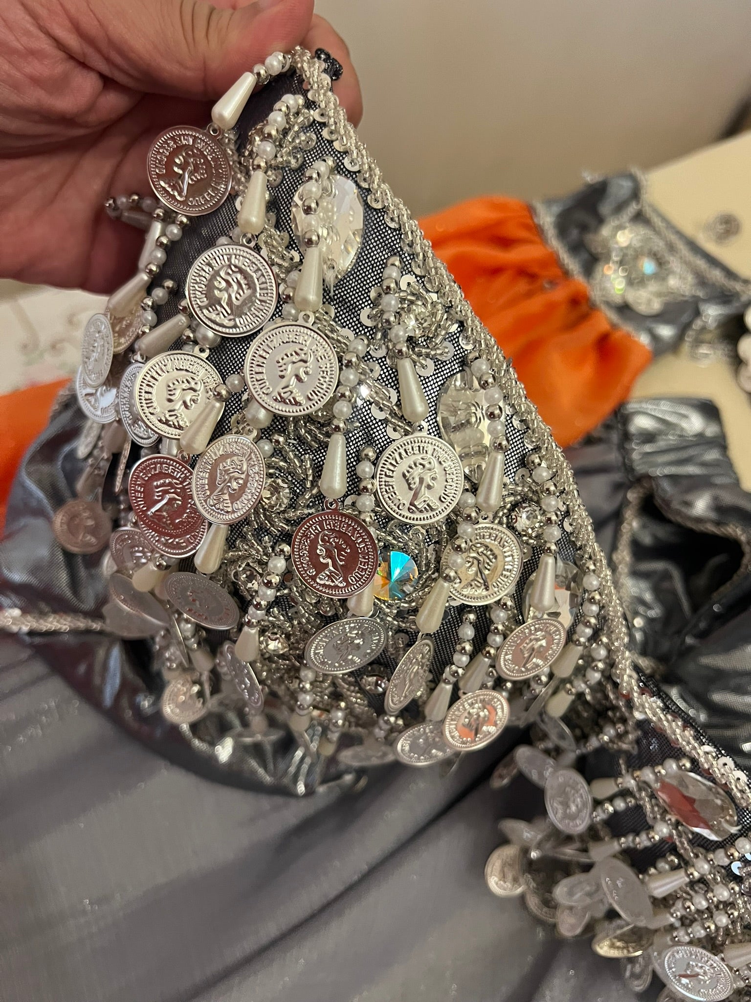 Decorative fabric with coins and embellishments held by a hand