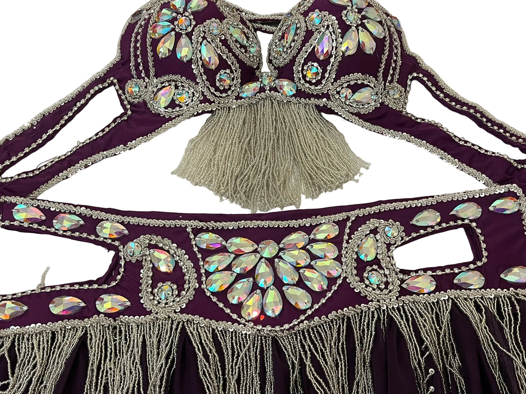 Decorative purple garment with silver beads and tassels on a white background