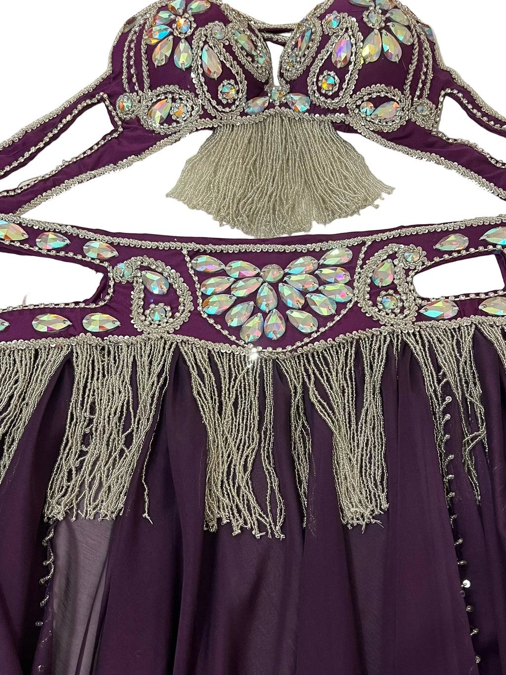 Purple garment with intricate silver embroidery and tassels on a white background