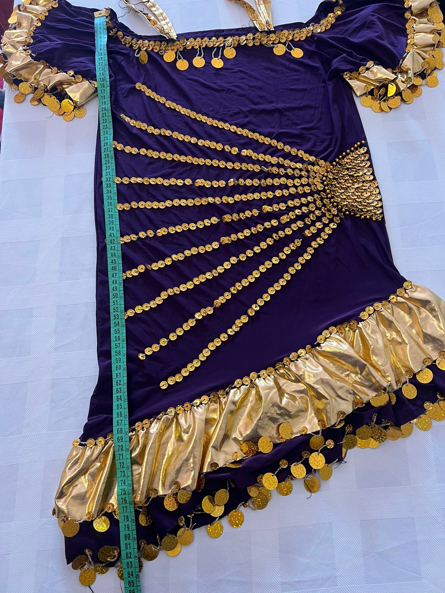 Purple dress with gold embellishments and a measuring tape on a white background