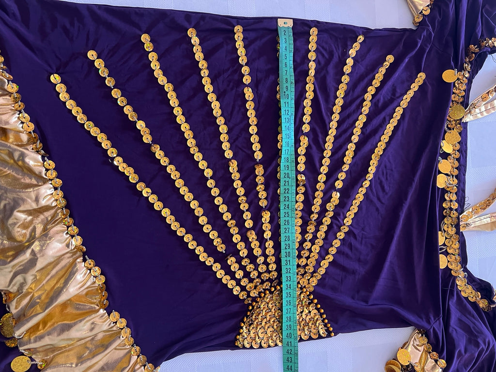 Purple fabric with gold embellishments and a measuring tape for scale on a white background