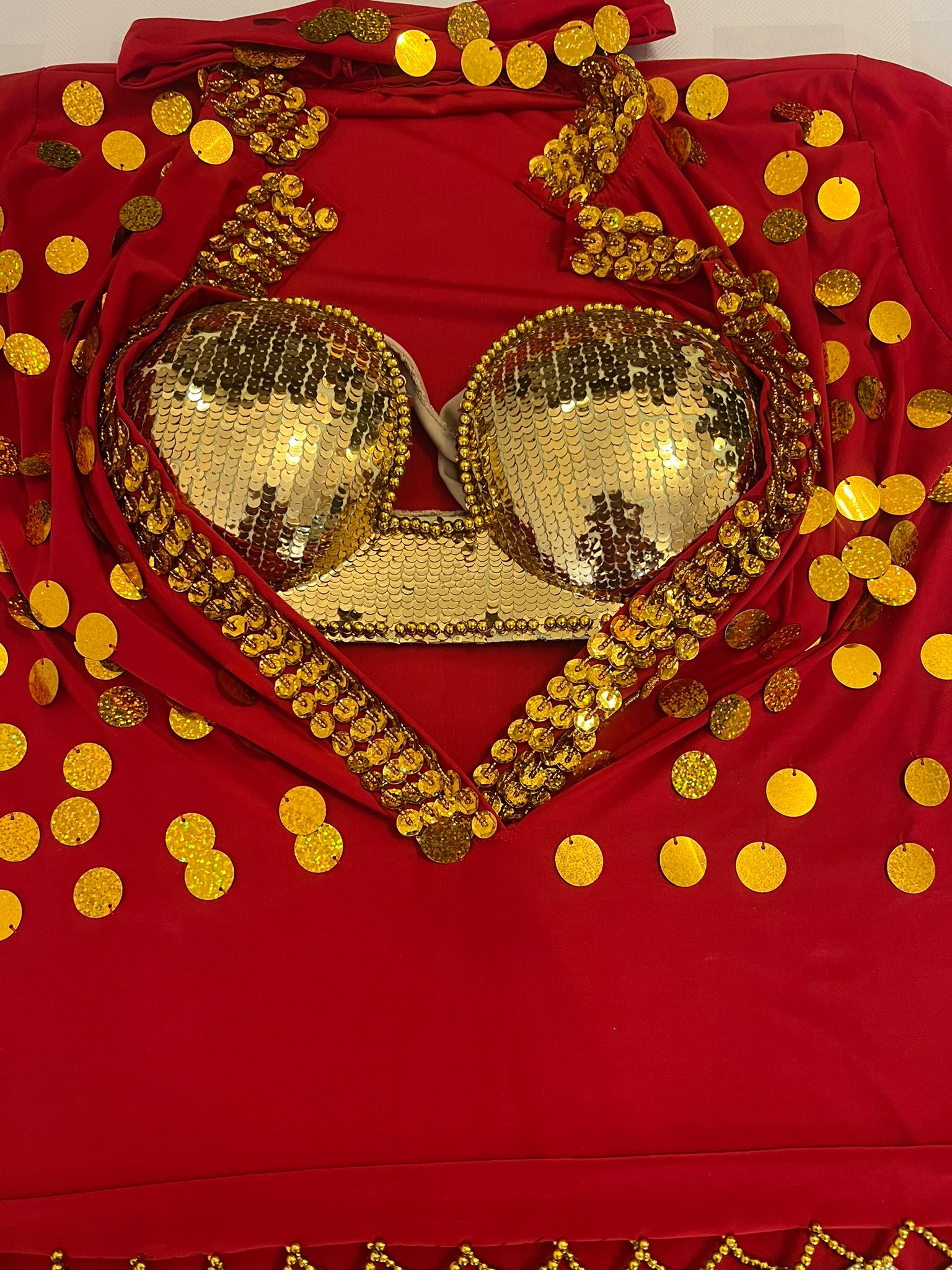 Gold sequin bra on a red fabric background with gold polka dots