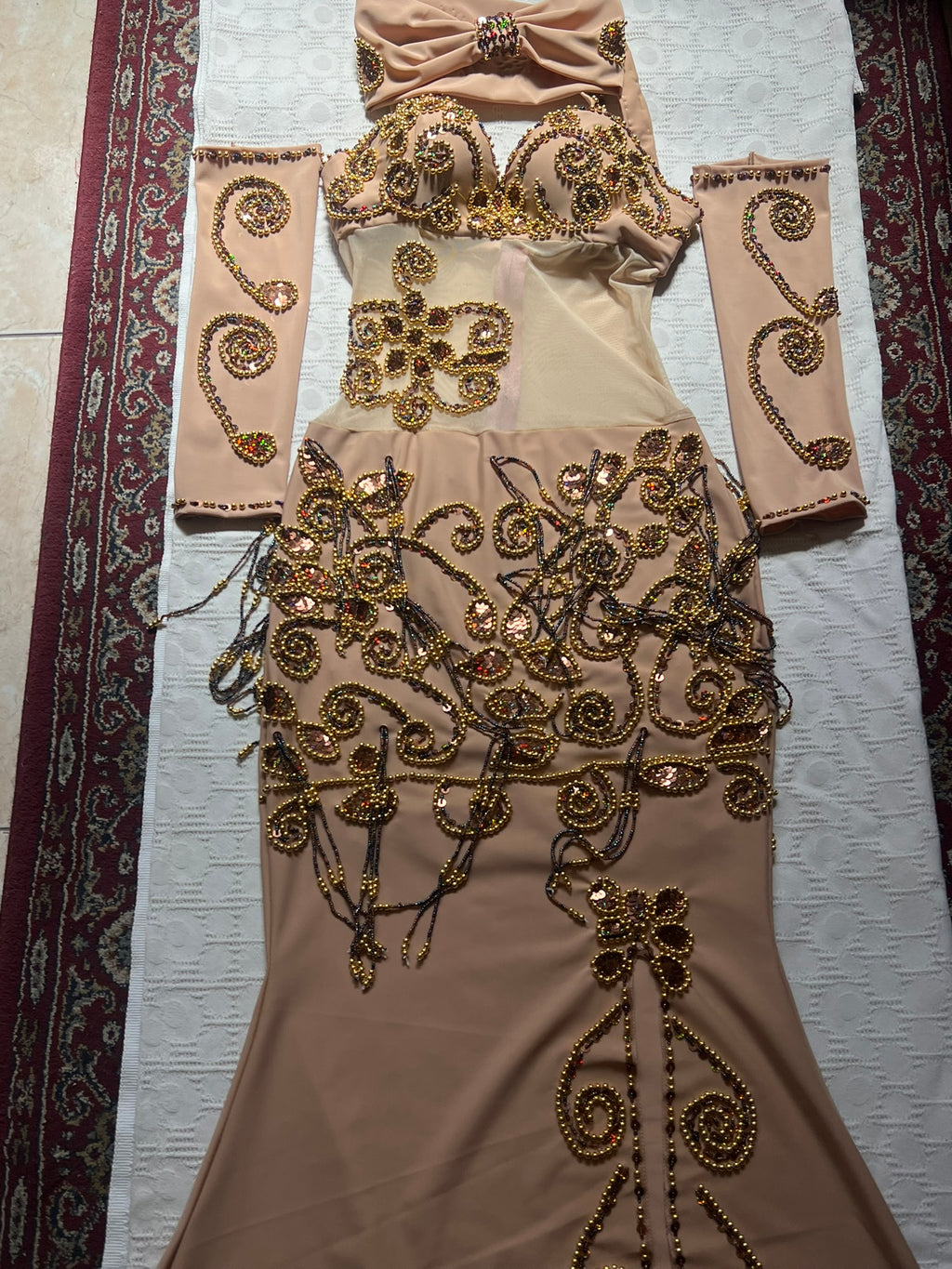 Beige evening gown with gold embroidery on a textured surface