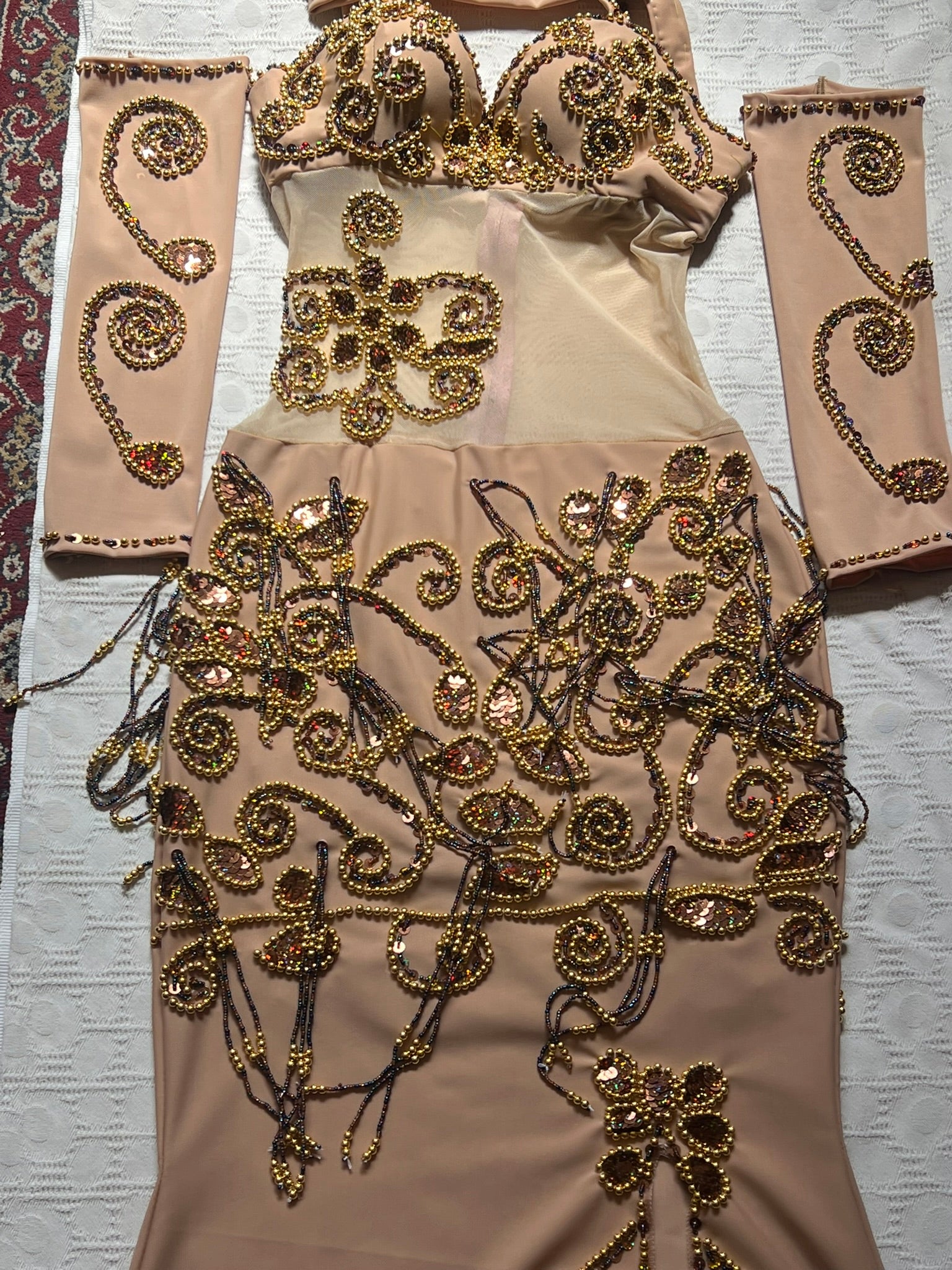 Beige outfit with gold embroidery on a textured surface