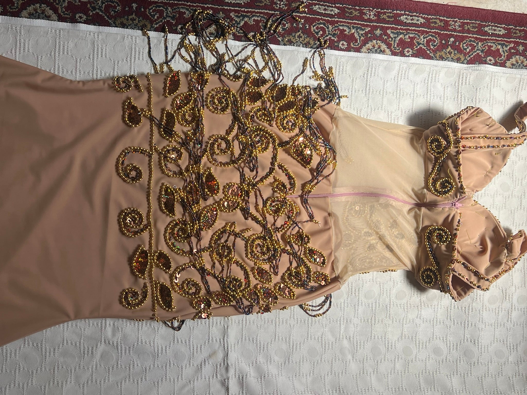 Backside view of Beaded dress on a white surface with a patterned rug in the background