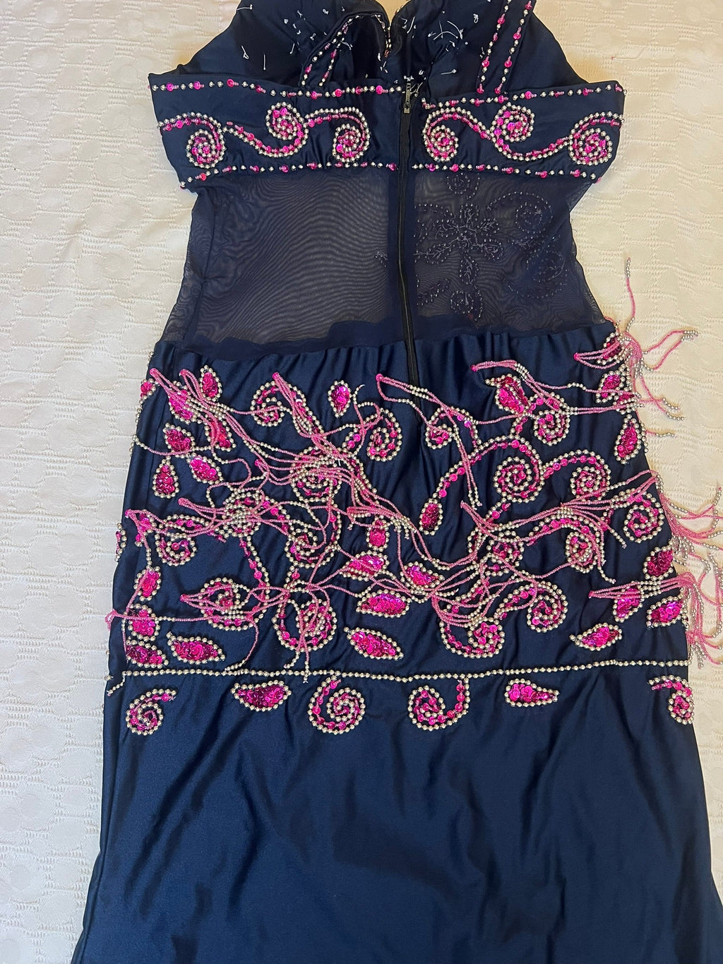Navy blue garment with pink and gold embroidery on a light background
