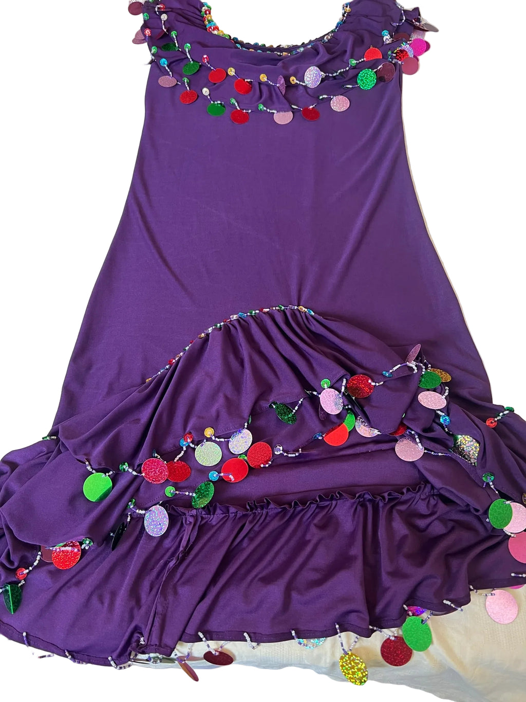 A purple belly dance dress with multicolored handmade embroidery decorations, displayed on a bed.