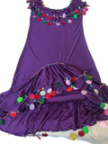 A purple belly dance dress with multicolored handmade embroidery decorations, displayed on a bed.