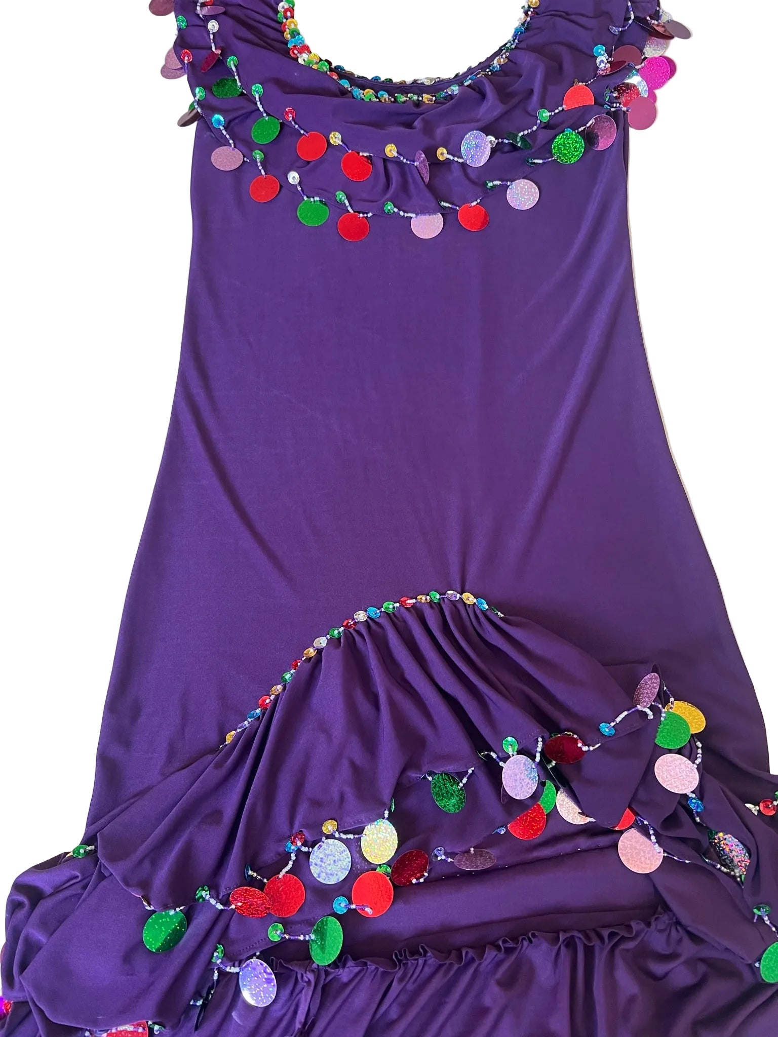 Purple dress with colorful pom-pom trim on a light gray surface