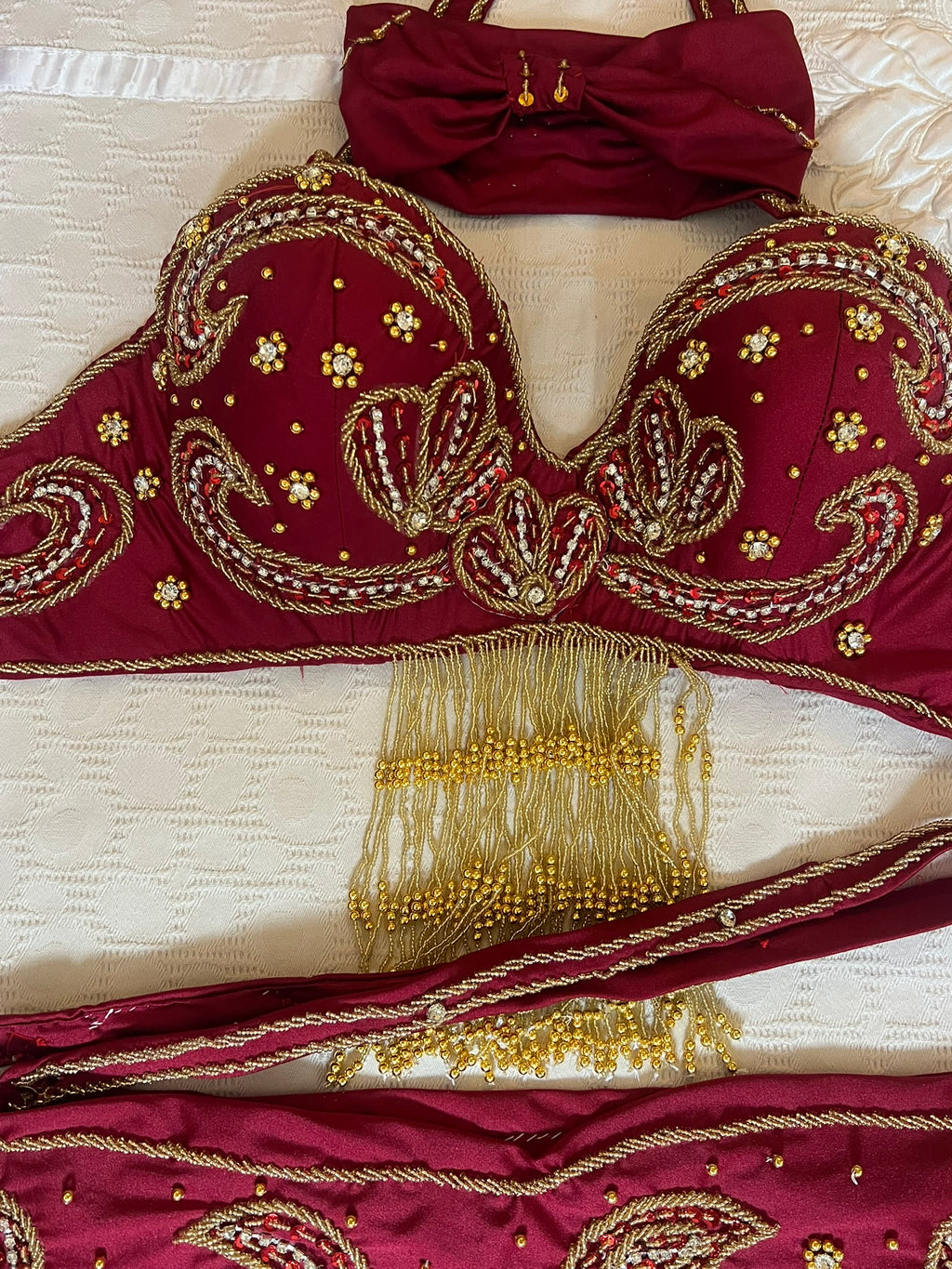 Maroon embroidered dance outfit with gold detailing on a white background