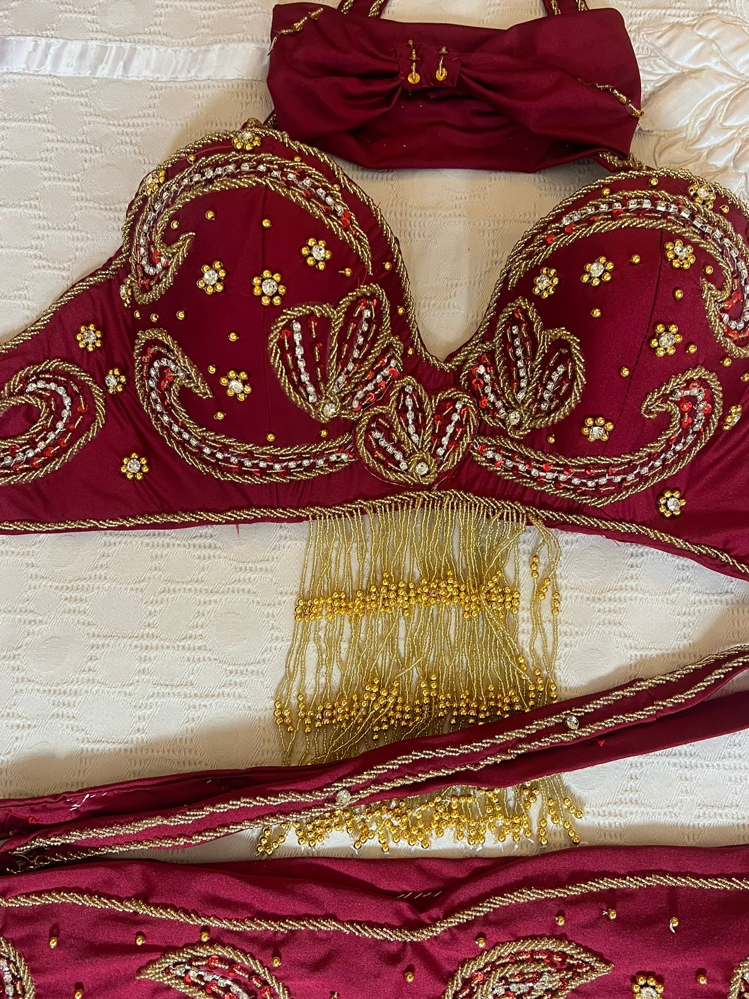 Maroon embroidered dance outfit with gold detailing on a white background
