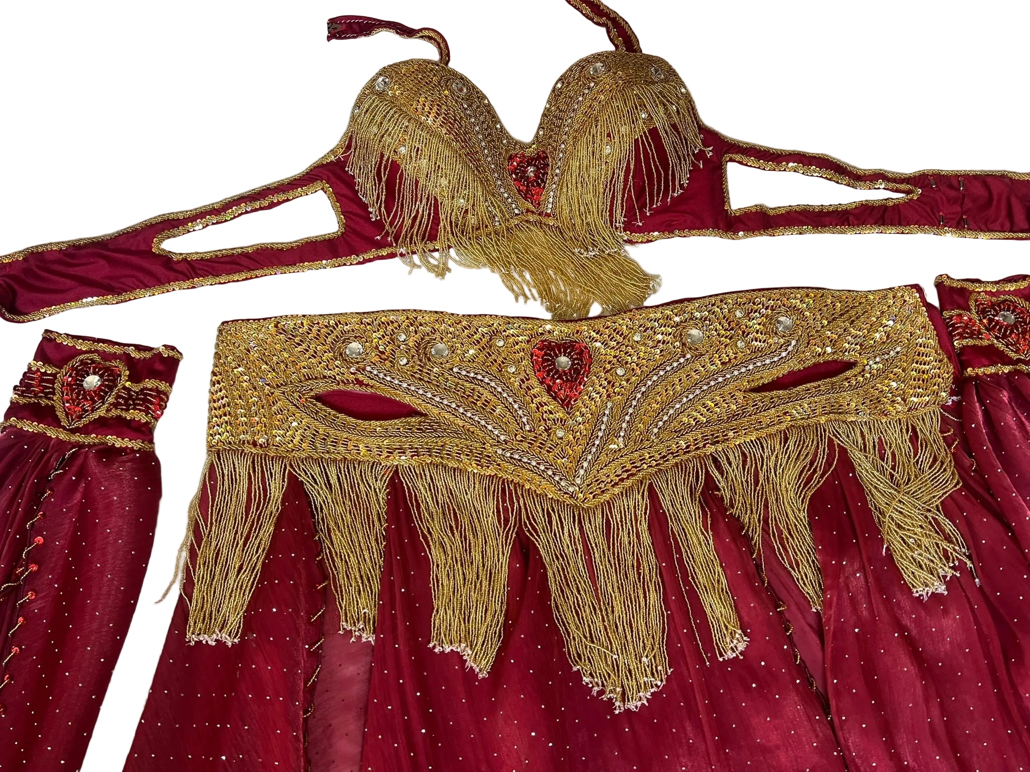 Decorative gold and red belly dance costume with intricate patterns and tassels on a textured white background