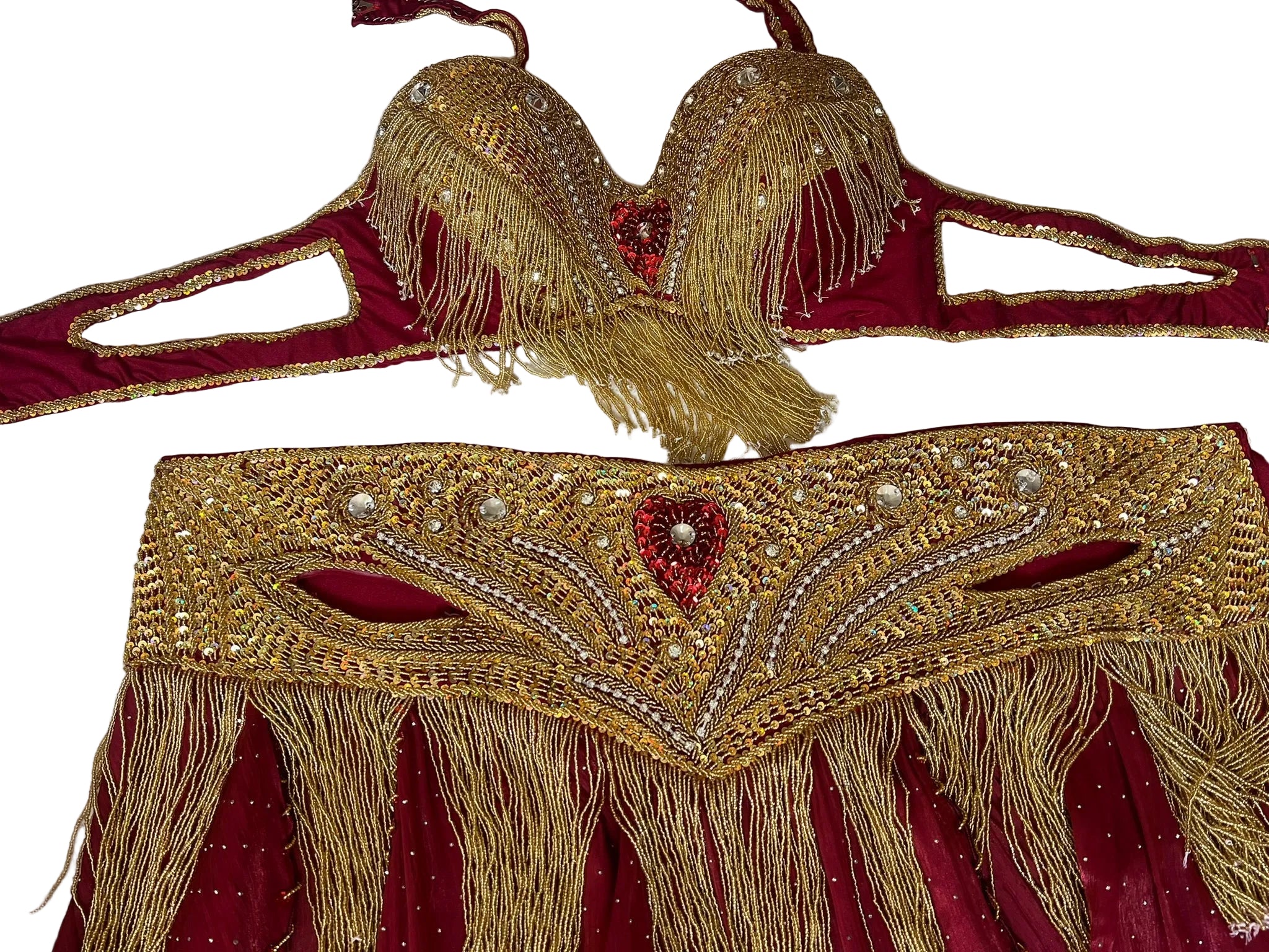Decorative gold and red belly dance belt and bra with intricate patterns on a textured white background