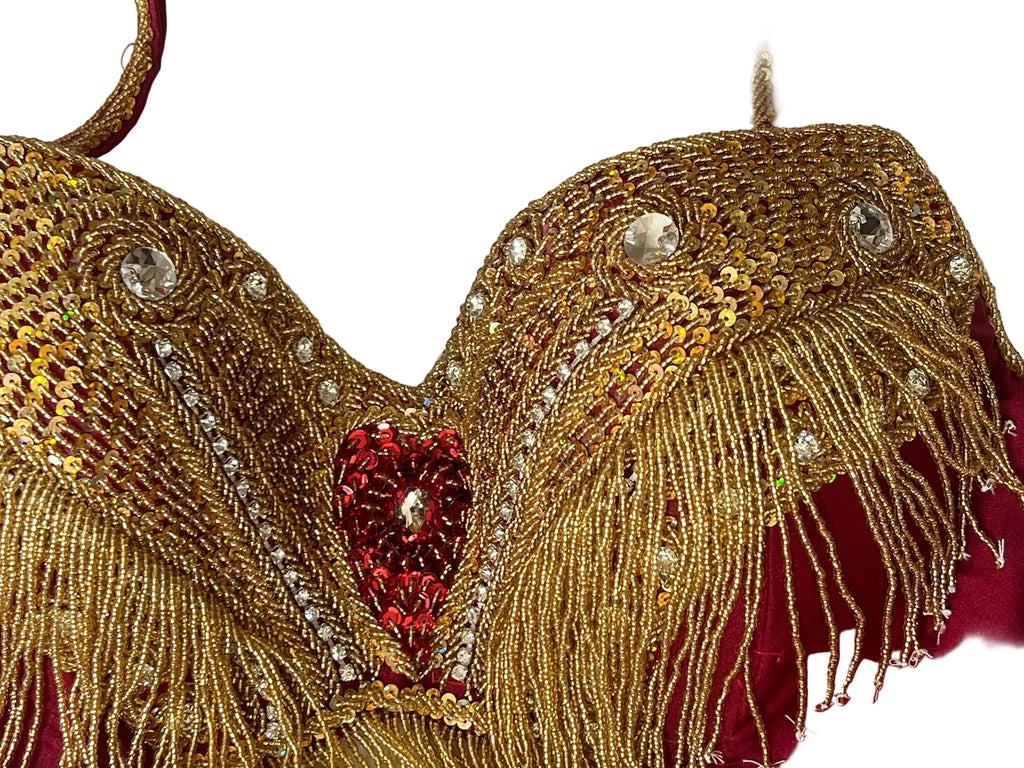 Decorative gold and red belly dance bra with intricate patterns on a white background
