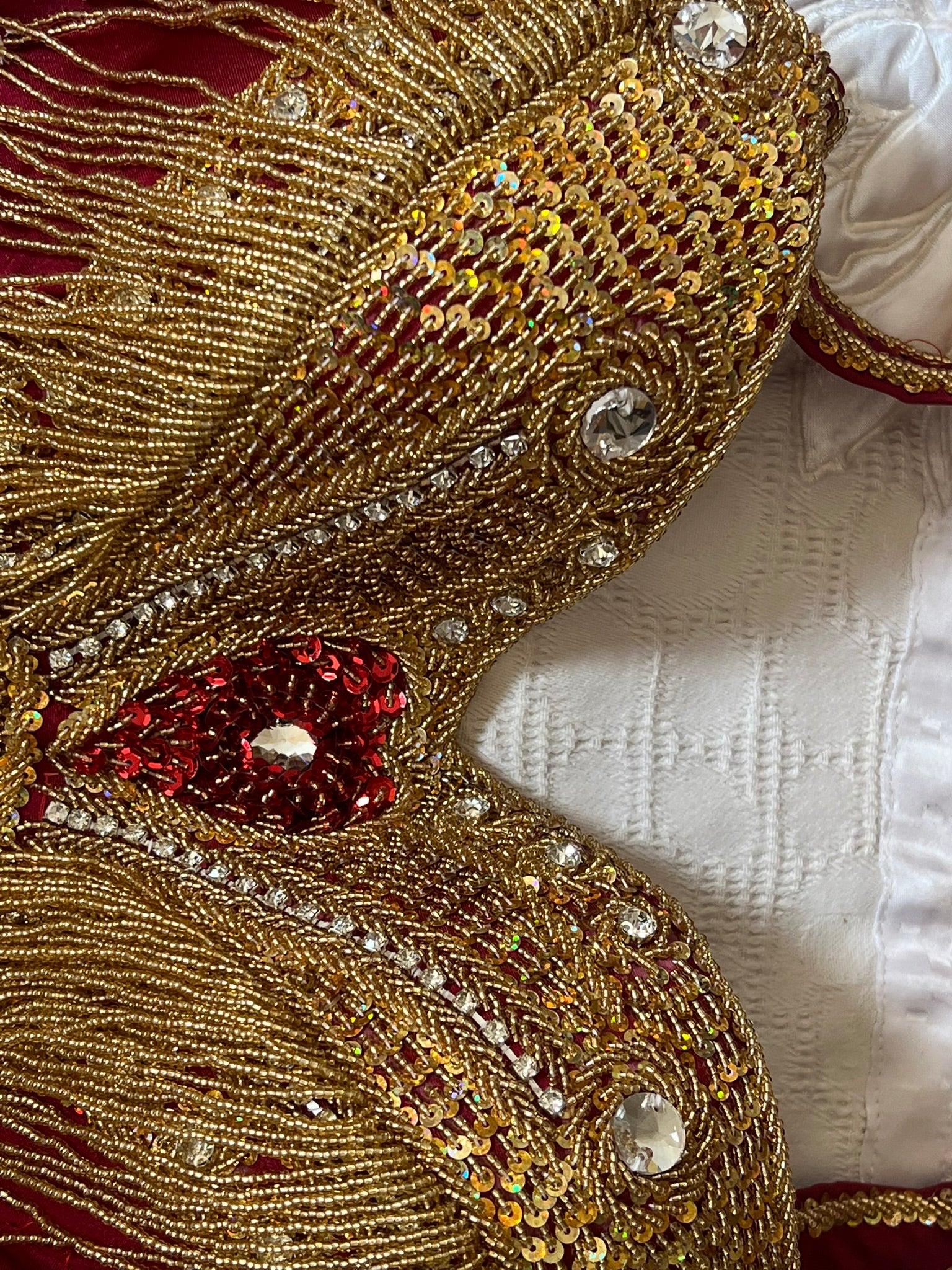Close-up of an intricately designed belly dance bra with gold, red, and white colors.