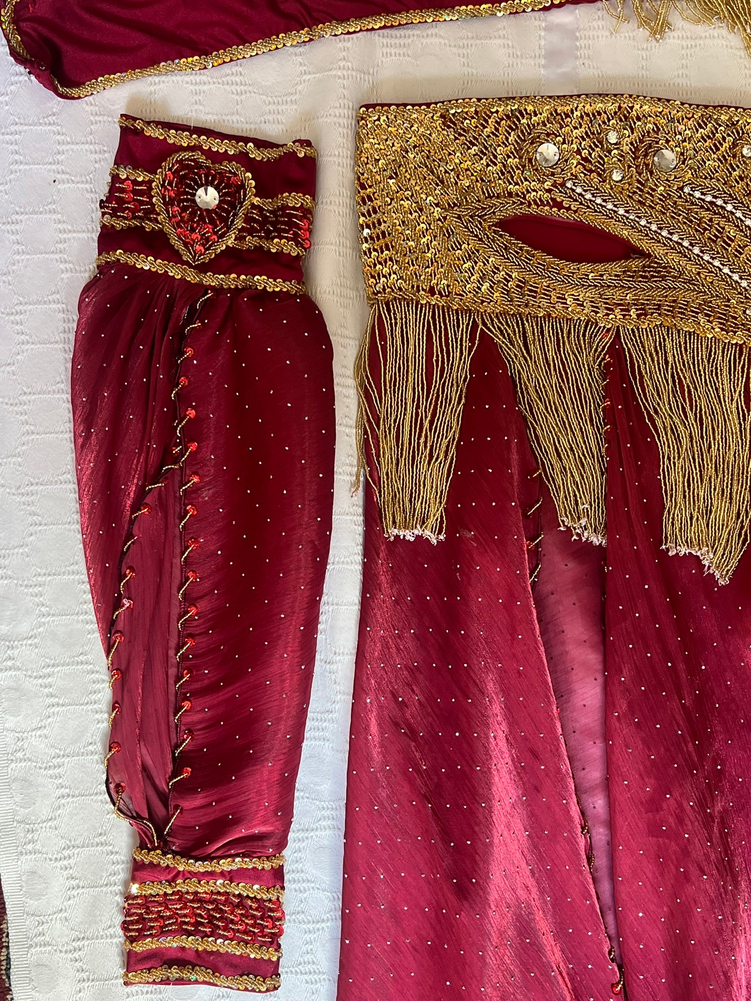Maroon traditional outfit with gold embroidery on a white background