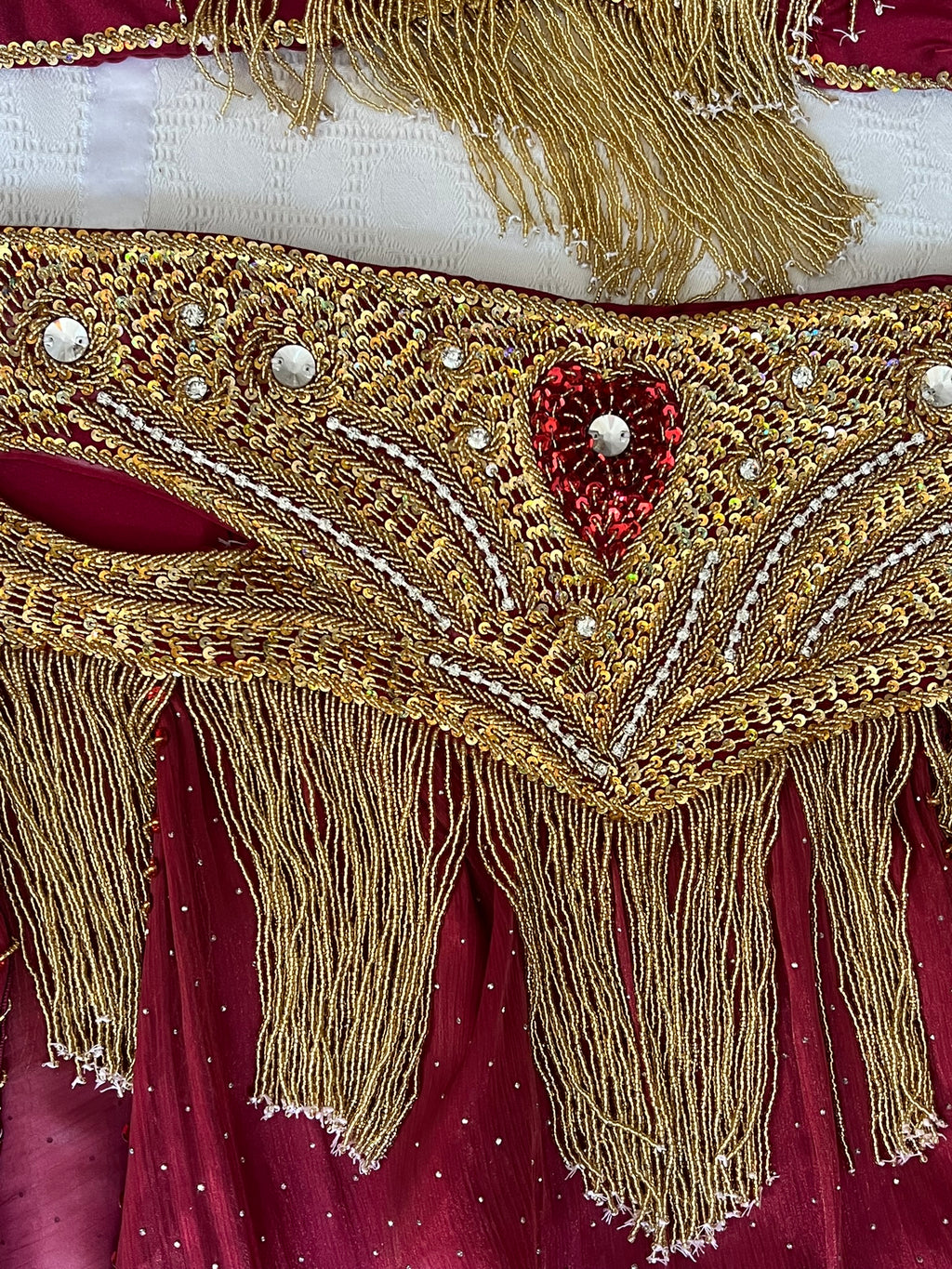 Decorative Belly dance belt with gold fringe and red heart design on a red fabric background