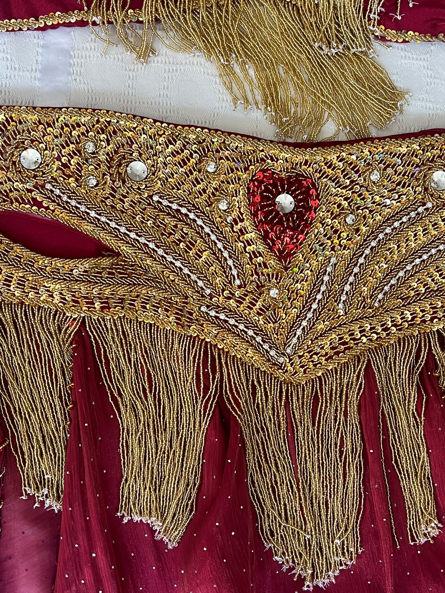 Decorative Belly dance belt with gold fringe and red heart design on a red fabric background